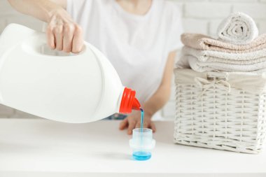 Kadın kapağa deterjan döküyor, yakın plan. Çamaşır konsepti