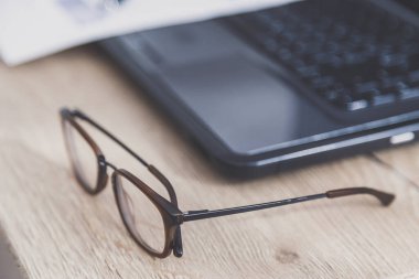 Ofis masası çalışma alanı. Tahta masadaki gözlüklerin yakın plan görüntüsü..
