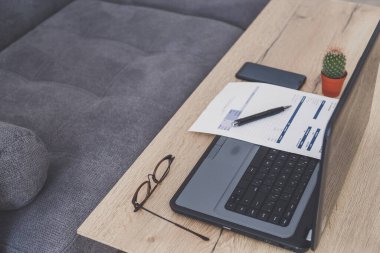 Ofis masası çalışma alanı. Diz üstü bilgisayar, fatura ve gözlükler ahşap masada..