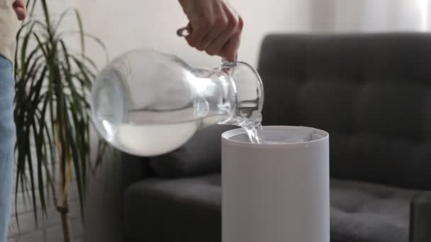 Un hombre vierte agua en un humidificador de aire vacío y esto continúa funcionando. Inicio microclima control — Vídeos de Stock