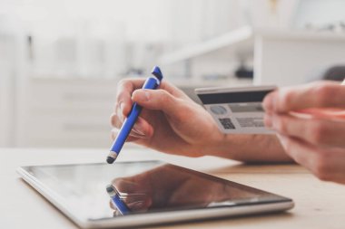 Tablet bilgisayar ve kredi kartını elinde tutan adam, online alışveriş yapıyor..