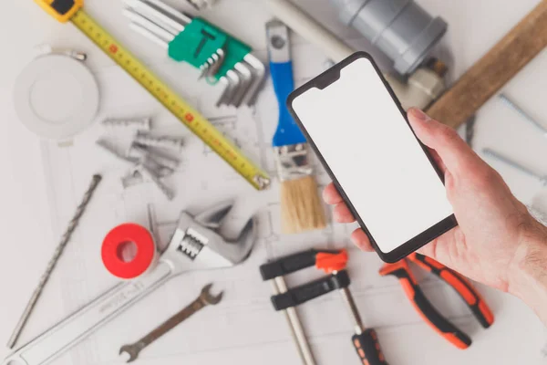 Smartphone com tela em branco com desenho e materiais de construção em segundo plano. — Fotografia de Stock