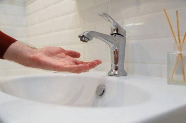 Elini suyun altında tutan adam musluğu susuz açtı. Ödenmemiş su kaynaklarının kapatılması veya merkezi sistemin onarımı sırasında.