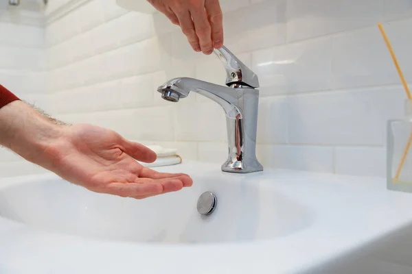 Elini suyun altında tutan adam musluğu susuz açtı. Ödenmemiş su kaynaklarının kapatılması veya merkezi sistemin onarımı sırasında.