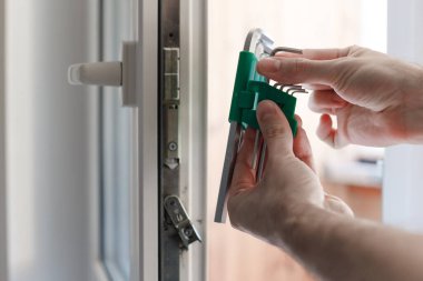 Erkekler, uPVC kapı mekanizmasının donanımının ayarlanması için allen anahtarını seçer