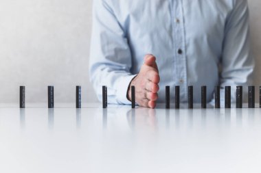 Adam domino taşının düşmesini engelliyor. Sosyal uzaklık ve yayılan virüsten tasarruf, konsept.