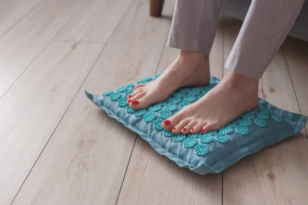 Kadın ayakları akupres minderinin üzerinde duruyor. Kendi kendine akupunktur masajı. Alternatif tedavi gören kadın.