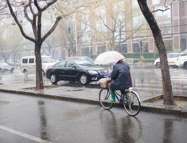 Islak bir karlı günde bir umbrells ile bisiklet sürme kişi.