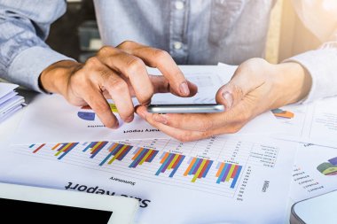 Akıllı telefon ile çalışma ve analizi grafikleri tartışan işadamı