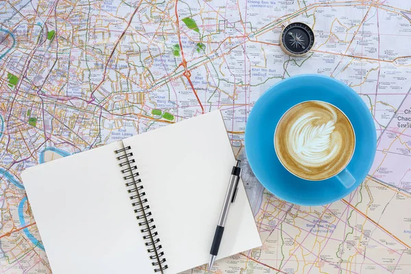 Hot coffee cup and compass on map
