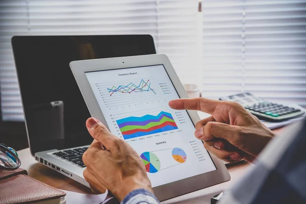 Bir tablet bilgisayar ekranında işadamı ve çalışma elinde finansal verilerle Close-Up.