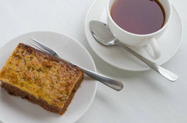 Bir fincan çay ile karamel fıstık tepesinde Brownie kek.