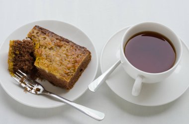 Bir fincan çay ile karamel fıstık tepesinde Brownie kek.