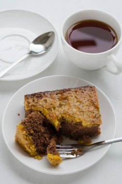 Bir fincan çay ile karamel fıstık tepesinde Brownie kek.