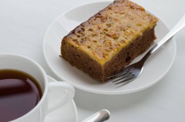 Bir fincan çay ile karamel fıstık tepesinde Brownie kek.