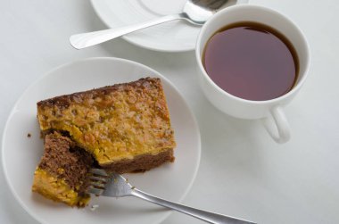 Bir fincan çay ile karamel fıstık tepesinde Brownie kek.