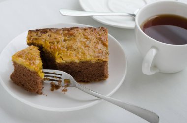 Bir fincan çay ile karamel fıstık tepesinde Brownie kek.