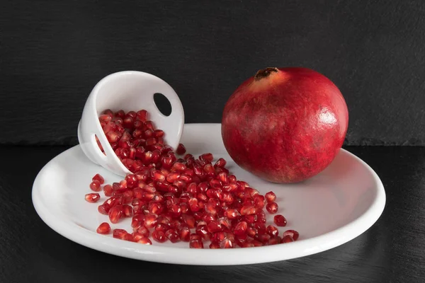 Sprinkled pomegranate on a white plate. — Stock Photo, Image