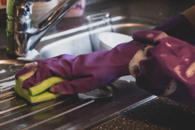 Mutfakta kirli bulaşıkları yıkıyor. 