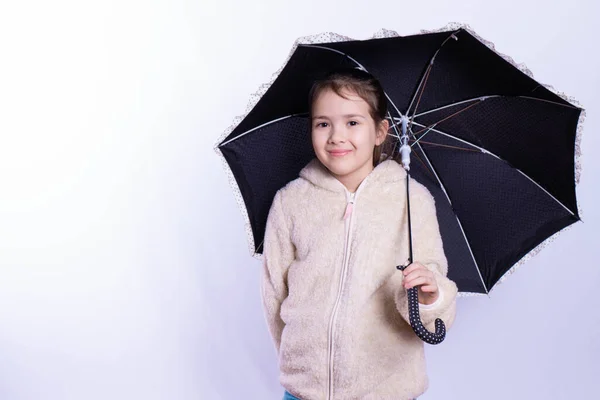 Niña con un paraguas negro sonríe — Foto de Stock