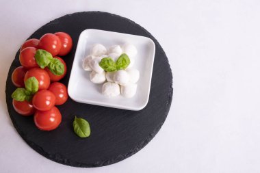 mozzarella ve domatesler beyaz arka planda bir masada.