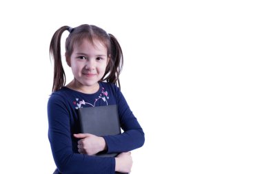 Küçük kız gülümsüyor ve beyaz arka planda bir tablete sarılıyor.