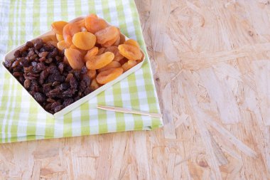 çeşitli kurutulmuş meyveler, kayısı, ahşap bir arka planda masa örtüsü üzerindeki kuru üzümler.