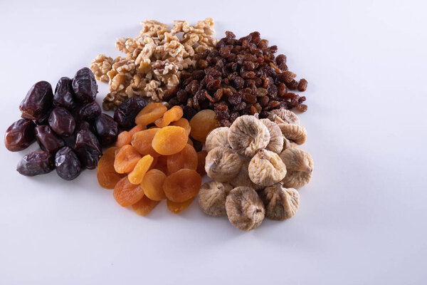 dried apricot, nuts, faygi, dates and raisins on a wooden background