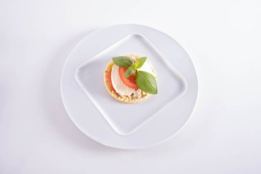 Bir tabakta fesleğen, mozzarella ve domates bulunur. Beyaz arka planda mısır gözlemesi.