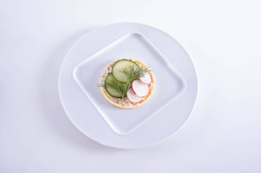 Bir tabakta salatalık ve turp uzanır. Beyaz bir zemin üzerinde mısır ekmeği.