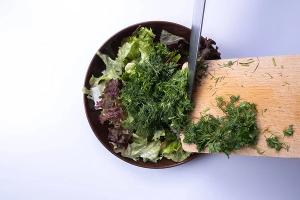 chopped salad and dill in a plate on a table on a white background