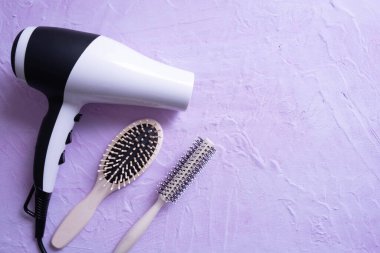 Saç kurutma makinesi ve taraklar dokulu arka planda ve her şey beyaz arka planda.