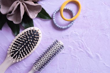 iki tarak, saç bandı ve yaprak süslemesi desenli bir arka planda uzanıyor ve her şey pembe bir arka planda.