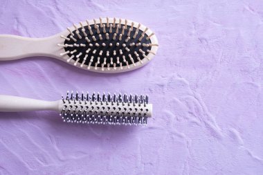 iki saç tarağı dokulu bir arka planda yatıyor ve her şey pembe bir arka planda.