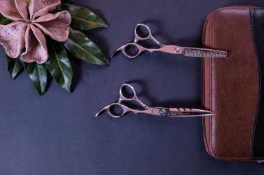 Bir kuaför için makas kahverengi deri bir çanta ve ahşap süslemeler dokulu bir arka planda yatıyor ve her şey mavi bir arka planda.