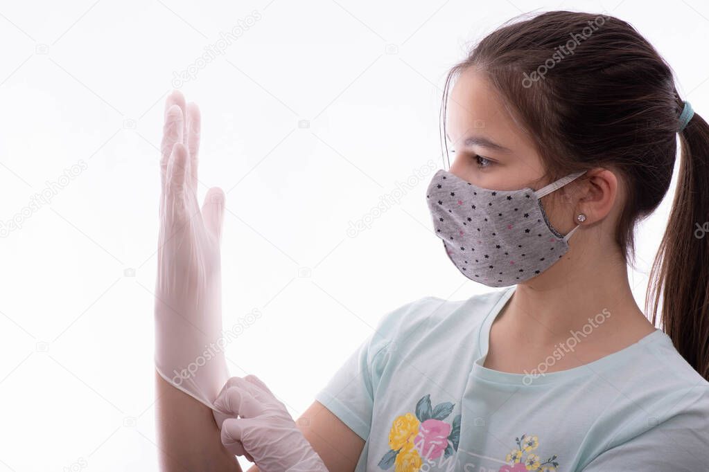 girl with a gray mask on her face puts protective gloves on her hands on a white background