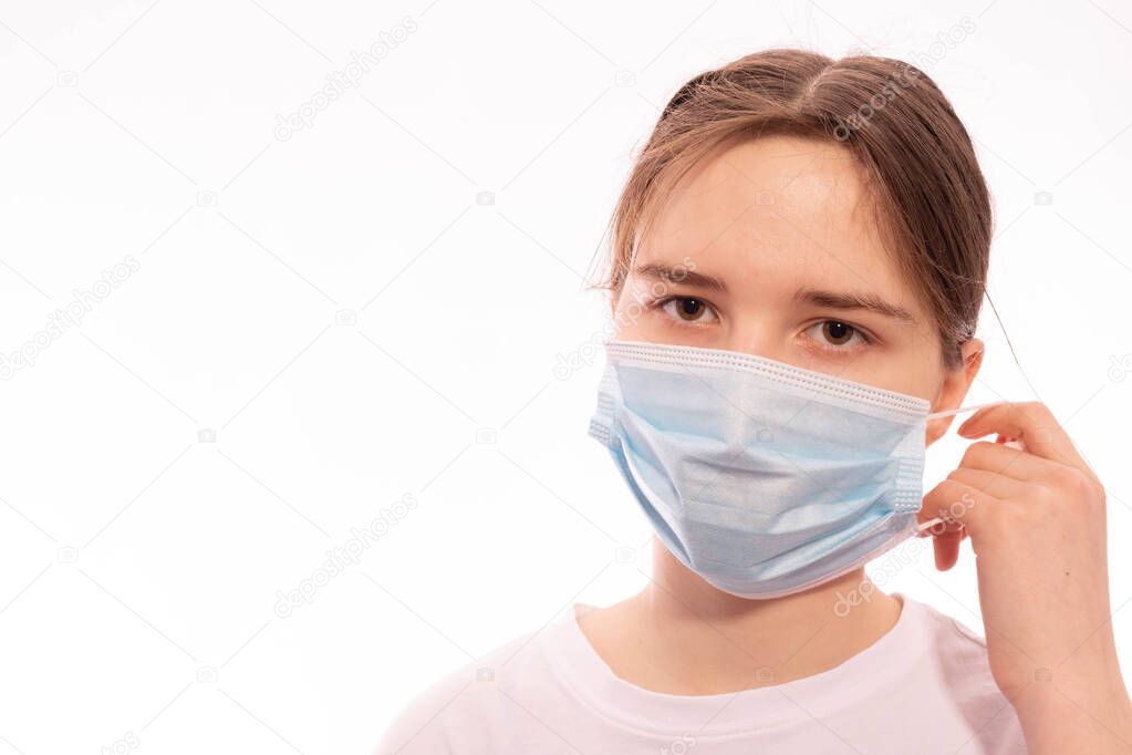 girl with a medical mask on her face removes it on a white background