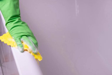 Eldivenli temizlikçi kadın beyaz arka planda banyo temizler ve yıkar.