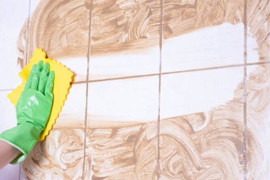 Kadın, beyaz arka planda kirli bir duvarı yıkıyor.