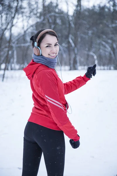 Female runner jogging in cold winter forest wearing warm sporty