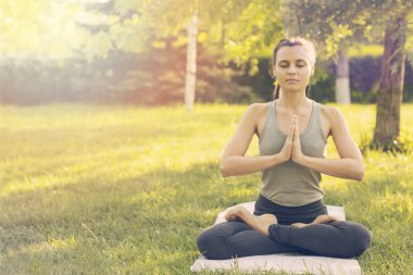 Park'ta yoga yapan beyaz bir kadın. Lotus pozisyonunda oturmak