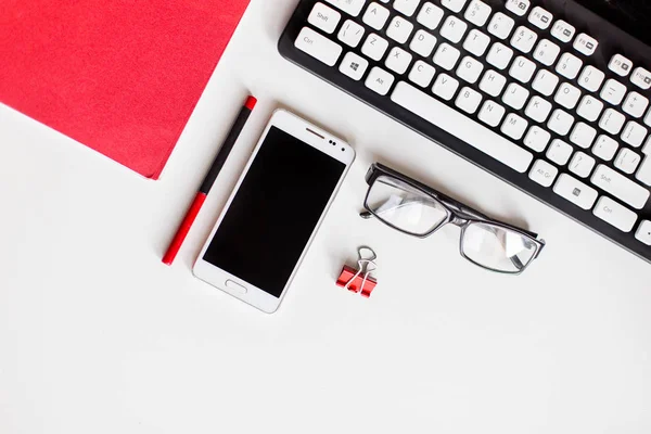 Телефон, окуляри, ручка, блокнот, клавіатура на офісному столі — стокове фото