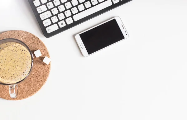 Tasse de café, téléphone portable et clavier sur la table de bureau — Photo