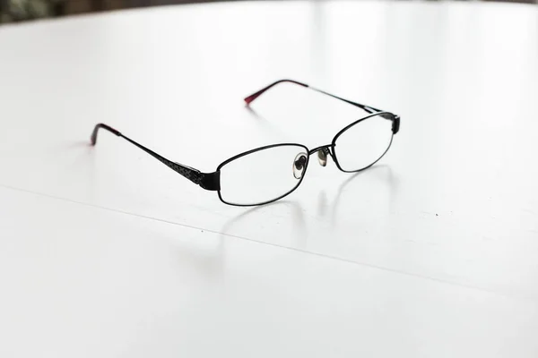 Bilder einer schwarzen Brille auf einem weißen Tisch — Stockfoto