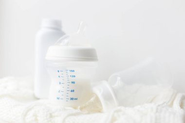 Bebek için aksesuarlar. Bir şişe süt hafif bir arka plan üzerinde