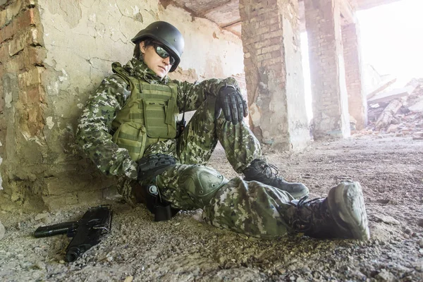 Voják sedí opřený o zeď v zřícené budovy. Vojenské konflikty — Stock fotografie