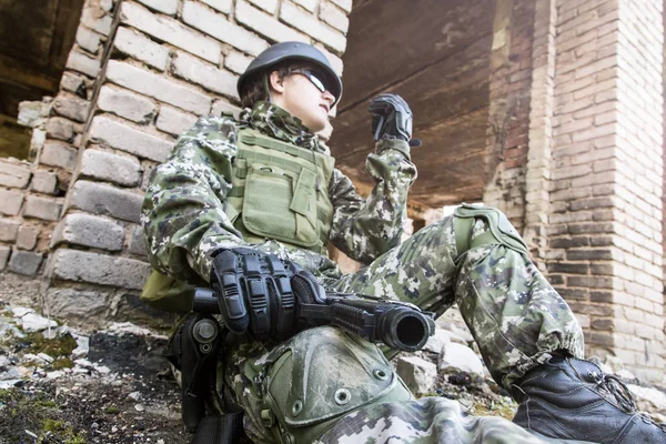 De soldaat gesprekken op de radio zit in een verwoeste gebouw. Militaire conflicten en communicatie — Stockfoto