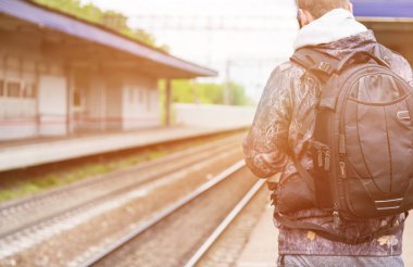 Bir sırt çantası ile tren istasyonundaki adama. Tren bekliyor