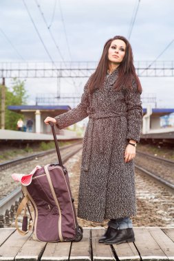 Tren istasyonunda bir çanta ile kız. Tren bekliyor