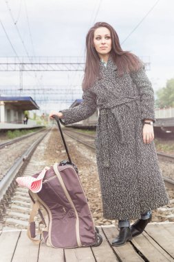 Tren istasyonunda bir çanta ile kız. Tren bekliyor